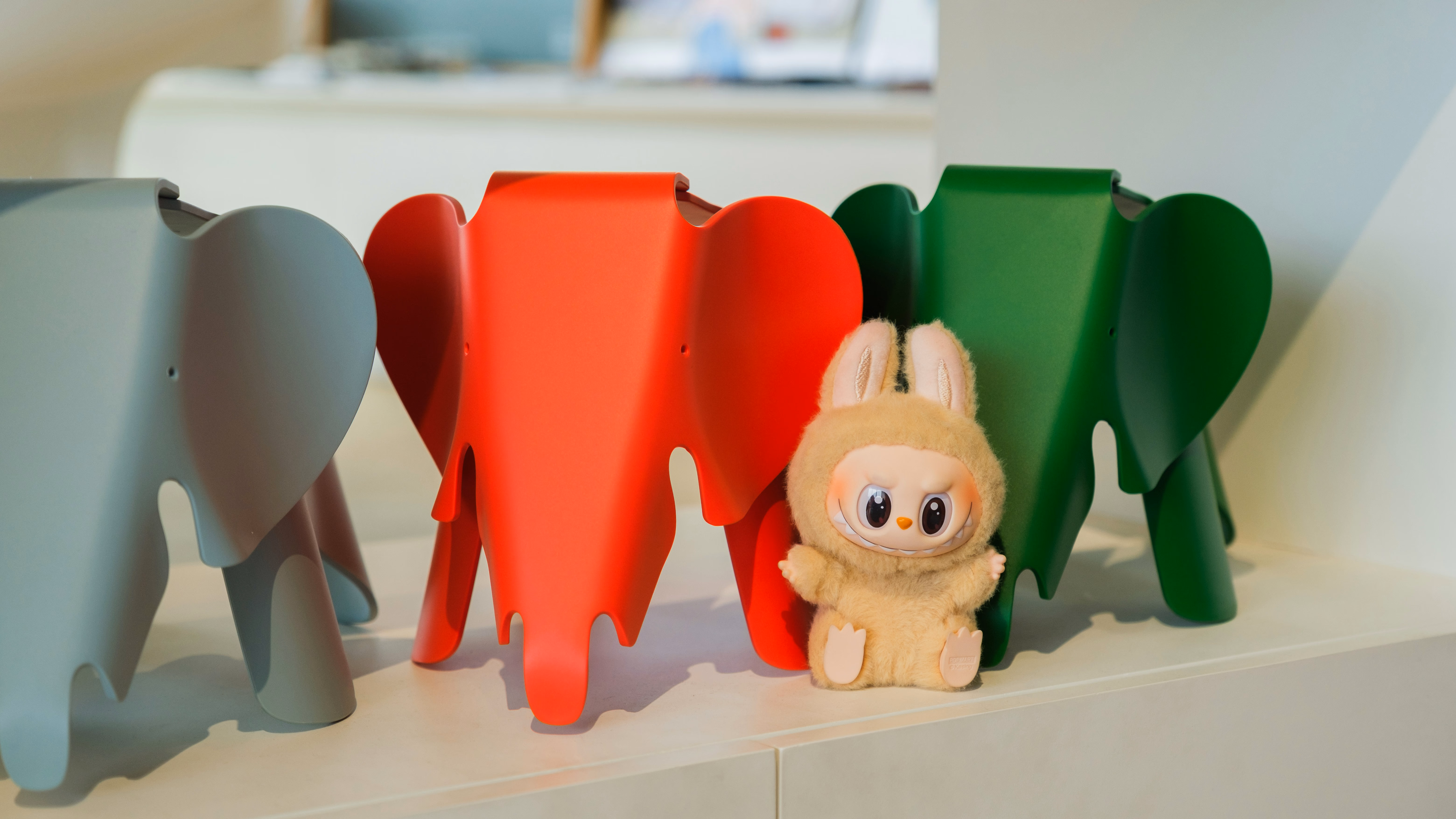 A labubu doll placing in front of 3 elephant-shape items